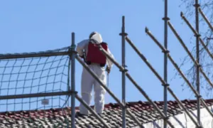 un 'addetto alla bonifica di una canna fumaria in amianto con dispositivi di sicurezza su un tetto