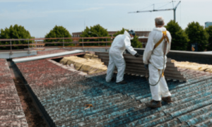 2 addetti alla rimozione di eternit sono posizionati su un tetto per bonificare l'area con appositi dispositivi ed attrezzi di sicurezza