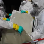 degli addetti attrezzati di dispositivi di sicurezza rimuovono delle lastre di eternit